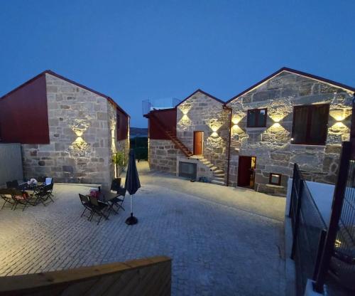 a stone house with a patio with a table and chairs at Casa de Penedones - Ventos de Barroso in Penedones