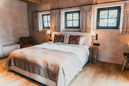 a bedroom with a large bed and two windows at B&B Extra Verte in Jabbeke