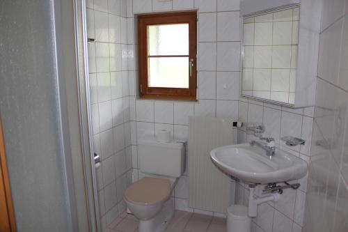 a white bathroom with a toilet and a sink at Chalet Good in Flumserberg