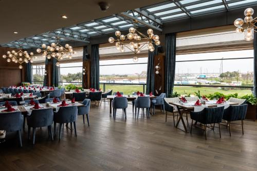 a dining room with tables and chairs and large windows at Dreamland Golf Hotel Baku in Baku