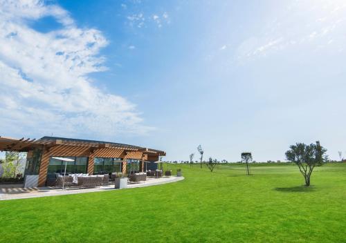 a building with a green field in front of it at Dreamland Golf Hotel Baku in Baku