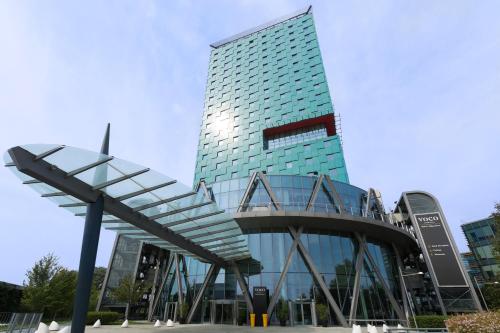 ein hohes Glasgebäude mit einer Treppe davor in der Unterkunft voco Milan-Fiere, an IHG Hotel in Mailand