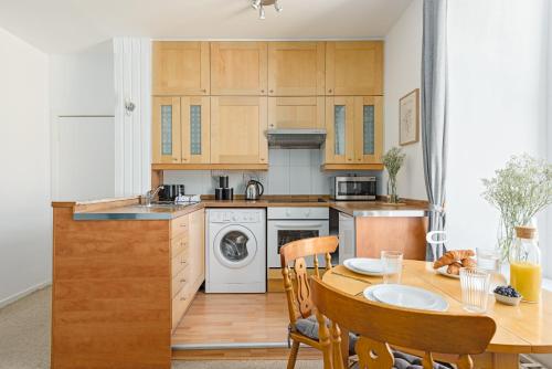 a kitchen with wooden cabinets and a table with chairs at The West Bow View Apartment in Edinburgh