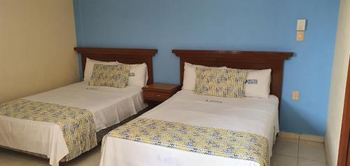 two beds in a room with blue walls at Hotel Dorado a una calle de Playa Regatas y el Malecon in Veracruz