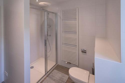 een witte badkamer met een douche en een toilet bij BEUKENHOUSE in Drogenbos