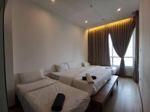 two beds in a hotel room with a window at ExcluSuites Malacca @ The Wave Residence in Melaka