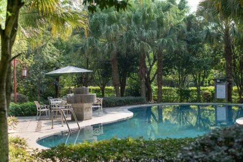 una piscina con mesa, sillas y árboles en Guilin Yi Characteristic Hotel CoLTD, en Guilin
