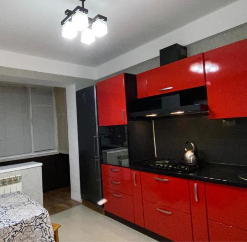 a kitchen with red cabinets and a stove top oven at Уютная квартира in Makhachkala