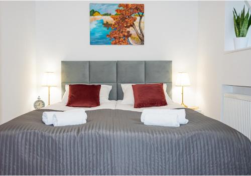 a bedroom with a large bed with two red pillows at Apartament Mała Wenecja in Barczewo