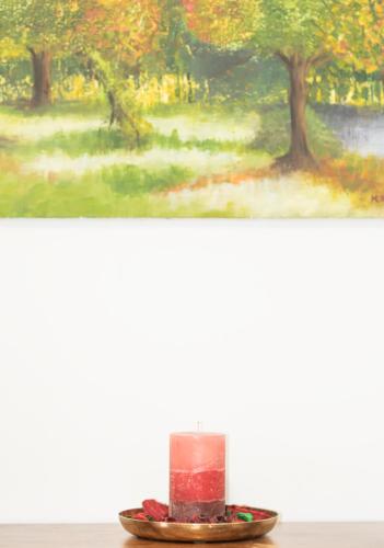 a red candle on a plate in front of a painting at Apartament Mała Wenecja in Barczewo