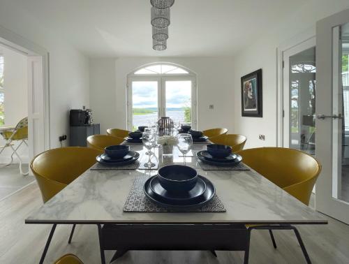a dining room with a table and yellow chairs at Escape Ordinary at Lily's Pad in Enniskillen