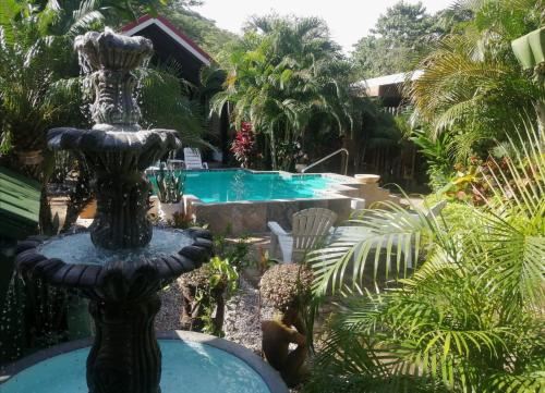 a fountain in the middle of a garden with a swimming pool at Suite Paraiso Azul in Tamarindo