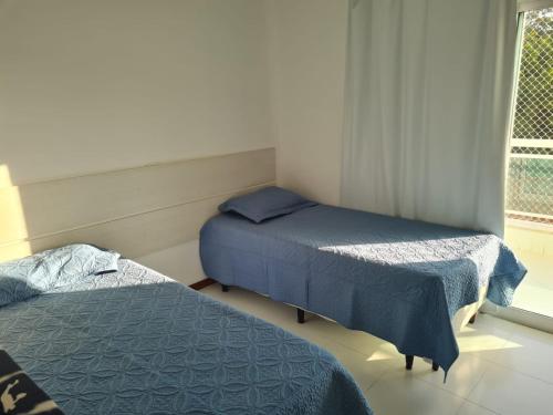 two beds in a small room with a window at Apto temporada Cabo Frio in Cabo Frio