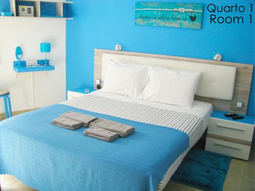 a blue bedroom with a bed with towels on it at Alojamento Tiago & Jorge Guesthouse in Nazaré