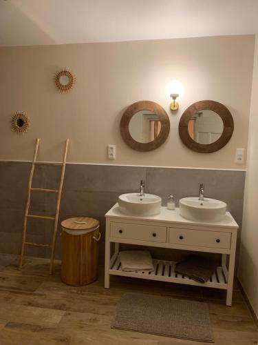 a bathroom with two sinks and two mirrors at Suite de caractère avec Jacuzzi in Milhaud