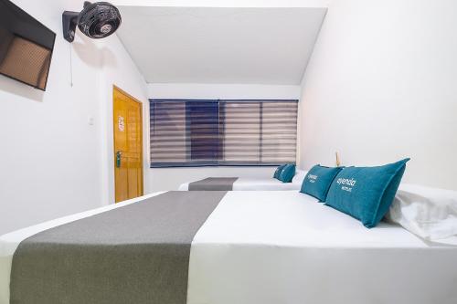 a bedroom with a large white bed with blue pillows at Hotel Antiguo Campestre in Bucaramanga