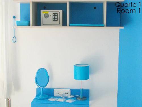 a room with a blue table with a mirror and a lamp at Alojamento Tiago & Jorge Guesthouse in Nazaré
