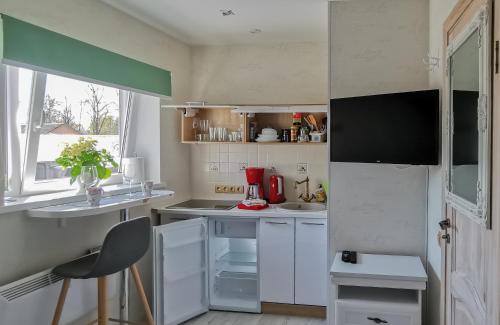 una pequeña cocina con armarios blancos y una ventana en Old Town Apartments en Jēkabpils