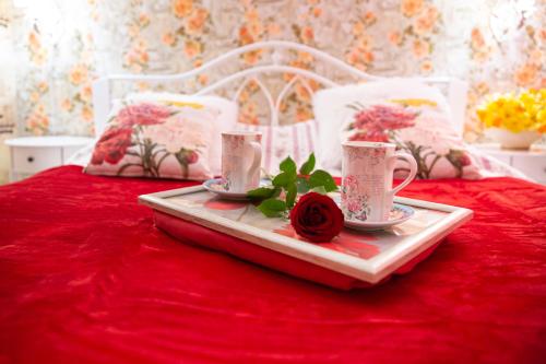 a tray with tea cups and a rose on a bed at Central Riverside Apartments in Jēkabpils