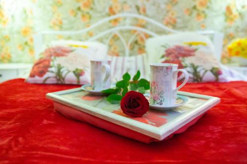 a tray with two cups and a rose on a table at Central Riverside Apartments in Jēkabpils
