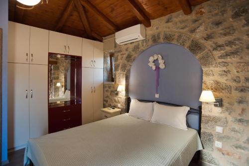1 dormitorio con 1 cama con pared de piedra en Lilea Chalet en Lílaia