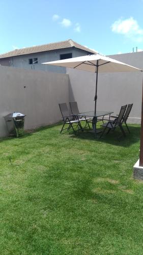 a group of chairs and an umbrella on a lawn at Condomínio Village 4 Carneiros casa 40 in Tamandaré