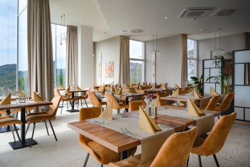 un restaurante con mesas, sillas y ventanas grandes en Crystal Mountain Hotel Wisła, en Wisła