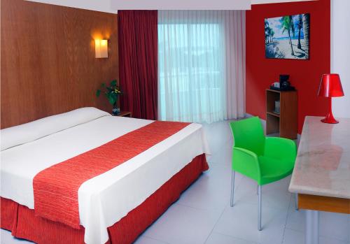 Habitación de hotel con cama y silla verde en Adhara Express en Cancún