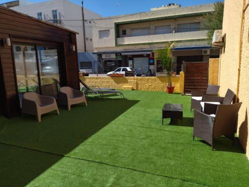 a patio with grass and chairs and a building at Hotel City Piriápolis in Piriápolis
