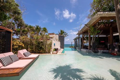 a pool at a resort with lounge chairs and the ocean at Mi Amor by La Zebra, an SLH Hotel in Tulum