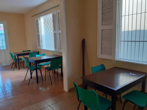 a dining room with tables and chairs and windows at Hostel Parquelândia in Fortaleza