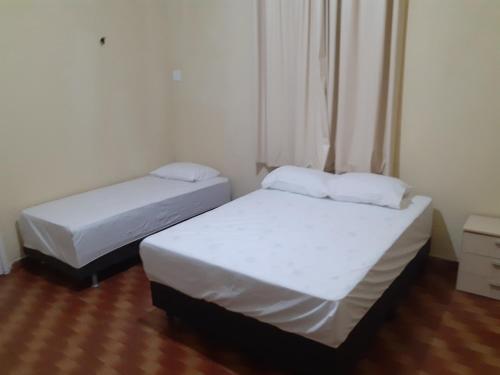 two beds in a small room with white sheets at Hostel Parquelândia in Fortaleza