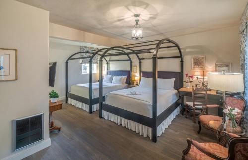 a bedroom with two beds and a desk and a room with a bedsenalsenal at L'Auberge Carmel, Relais & Chateaux in Carmel