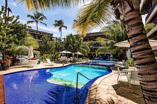 una piscina con una palma accanto a un resort di Nannai Residence by AFT a Porto De Galinhas