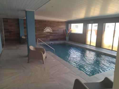 uma grande piscina num quarto com cadeiras em Hotel City Piriápolis em Piriápolis