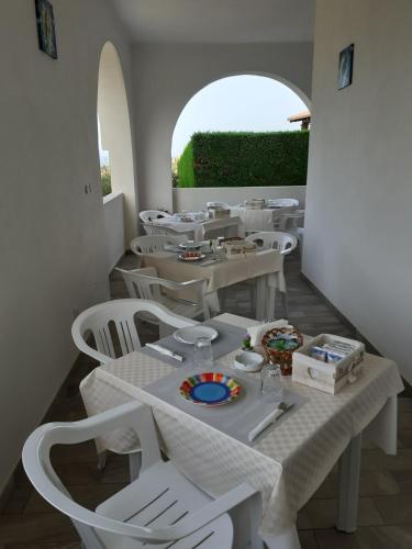 un restaurante con mesas blancas y sillas blancas en La Conchiglia en San Nicola Arcella