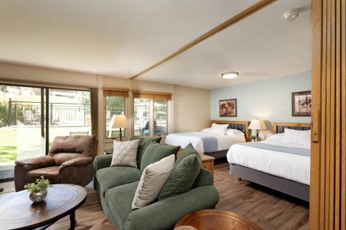 a hotel room with two beds and a green couch at Lichenhearth 26 in Snowmass Village
