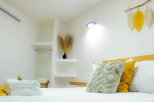 Schlafzimmer mit einem Bett mit weißer Bettwäsche und gelben Kissen in der Unterkunft Very Special Place Apto in Guatemala