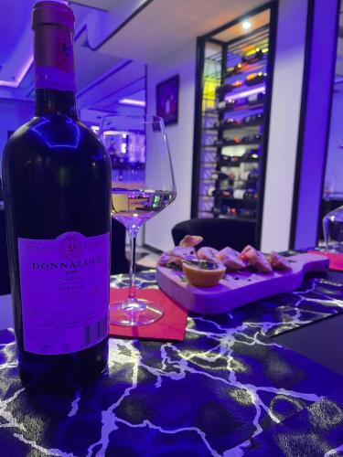 a bottle of wine sitting on a table with a plate of food at Garden Boutique Hotel in Elbasan