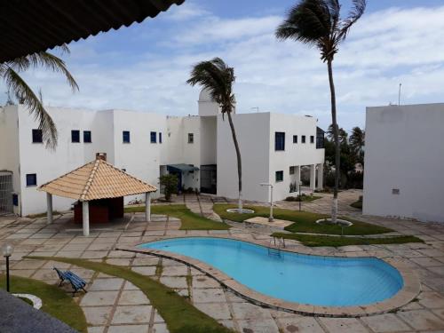 a resort with a swimming pool and palm trees at Porto Canoa Apartamento in Aracati