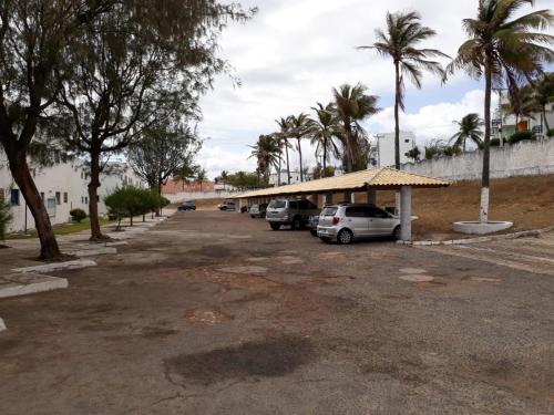a parking lot with parked cars and palm trees at Porto Canoa Apartamento in Aracati