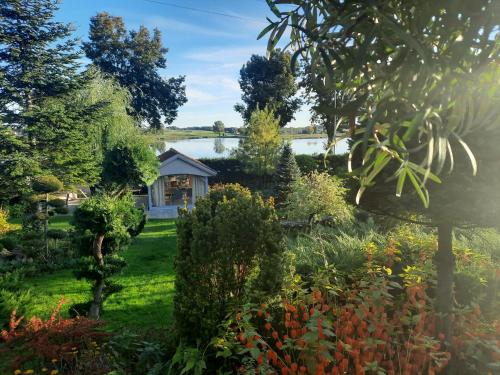 a garden with a house and a lake in the background at Apartamenty Sielanka in Olecko