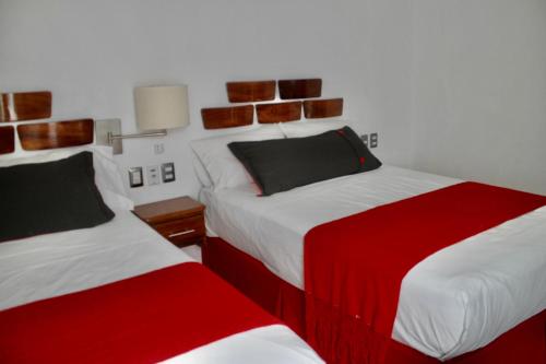 two beds in a room with red and white at Melaque Paradise in San Patricio Melaque
