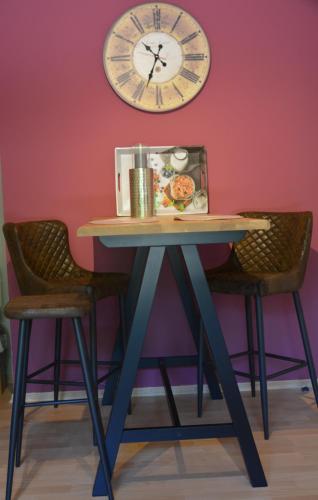 a table with two chairs and a clock on the wall at Ferienwohnung im Storkenbusch in Beckingen