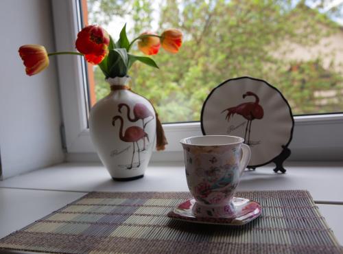 a vase and a cup on a table with a window at Central Riverside Apartments in Jēkabpils