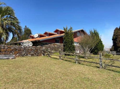 a red house with a stone wall and a fence at Fazenda Rodeio Bonito in Lages