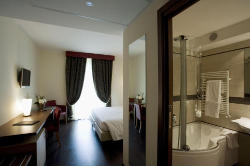 Red's Redaelli Hotel في Barzanò: غرفة في الفندق مع سرير وحوض استحمام