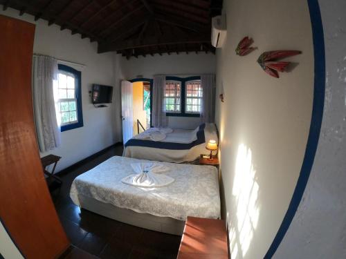 a bedroom with two beds and two windows at Pousada Aquamaster Dive Center in Angra dos Reis