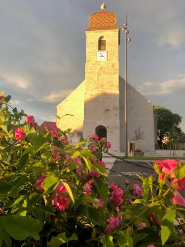 a church with a tower with a clock on it at Hôtel D’Artiste in Pierrefontaine-les-Varans