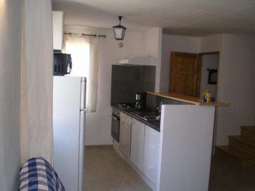 Il comprend une cuisine équipée d'appareils électroménagers blancs et d'un réfrigérateur blanc. dans l'établissement Les Cigales d'Estoublon, à Estoublon